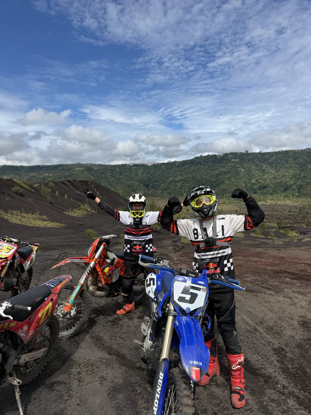 Top of the climb | Two riders celebrating beside their dirt bikes on the volcanic slopes of the Kintamani highlands in Bali, sober adventure travel, Nomadic Addictt.