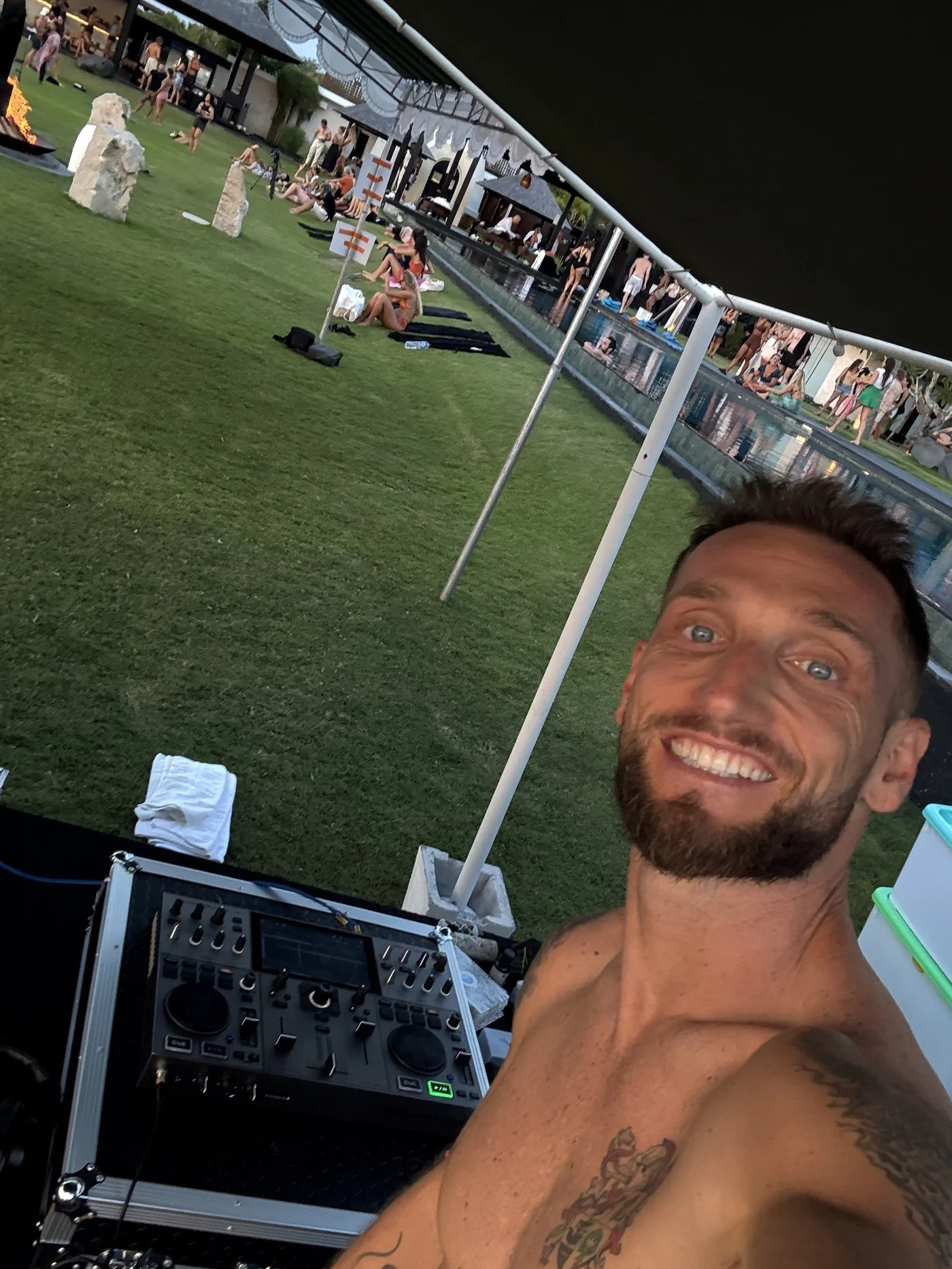 Getting set up for a sunset silent disco DJ sesh. Me smiling in a selfie behind the DJ decks, setting up for a sunset silent disco by the pool